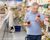 Focused aged man reading labels on bottles of sauce in supermarket, carefully examining ingredients and expiration date while shopping for groceries.